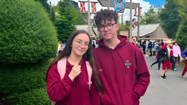 Dos personas están en una calle con varios edificios de fondo en el terreno de la St. Ciarán’s Community School.