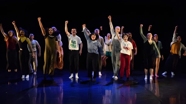 Estudiantes de St. Coleman's College están en un escenario con los brazos en alto y realizan una actuación vibrante.