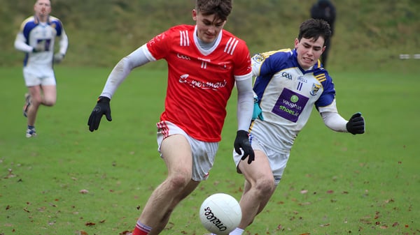 Dos futbolistas en camisetas rojas y azules juegan en el campo deportivo del St. Colmans College.