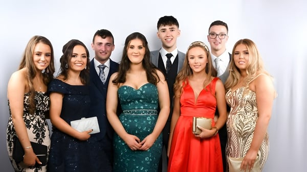 Un grupo de personas bien vestidas posan juntas frente a un fondo blanco en el St. Columba's College.