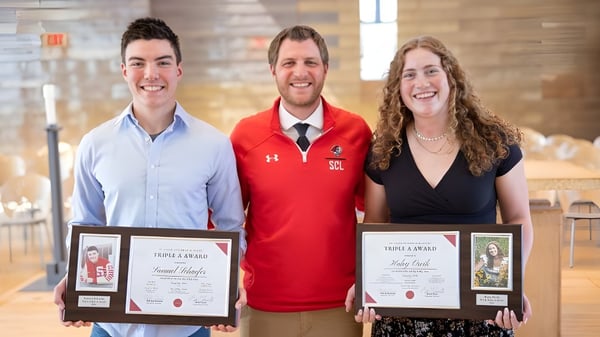 Tres personas sostienen certificados durante la entrega de premios en el campus de la St. Croix Lutheran Academy.