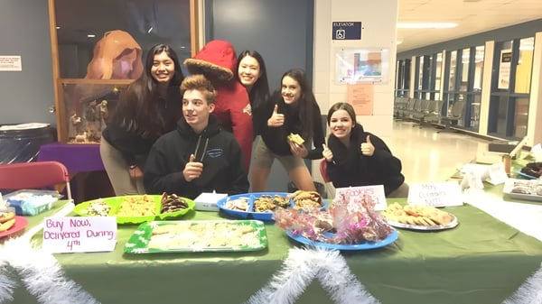Estudiantes de la St. David Catholic Secondary School venden muffins en una mesa con el cartel 'Buy Muffins Donate Diapers'.