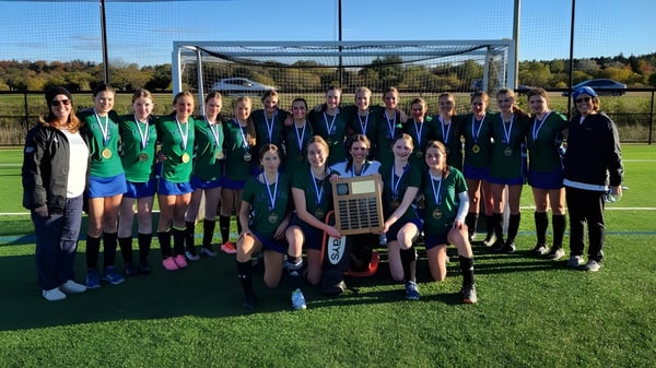 Un grupo de estudiantes de la St. David Catholic Secondary School está en el campo de fútbol frente a la portería.
