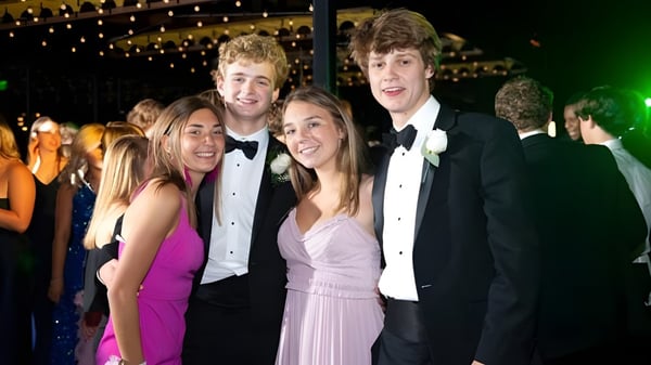 Un grupo de estudiantes del St. David’s College posan juntos en vestimenta festiva frente a un fondo con luces brillantes.