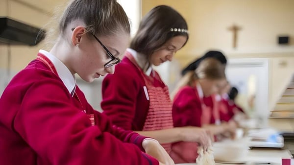 Estudiantes del St. Dominic’s College llevan túnicas rojas y están ocupados en una discusión grupal.