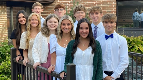 Un grupo de estudiantes posa frente a un edificio de ladrillo en el terreno de la St. Edmond Catholic School.