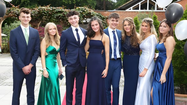 Un grupo de estudiantes bien vestidos posan juntos frente a un fondo verde en el campus de la St. Edward's School en Poole.
