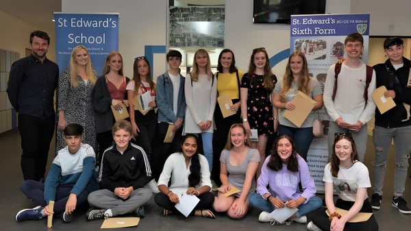 Un grupo de estudiantes está frente al logo de la St. Edward's School en Poole durante un evento escolar.