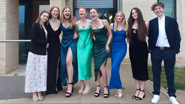 Un grupo de estudiantes de la St Edward's School Oxford está vestido de forma formal frente a un edificio moderno y posan para una foto.