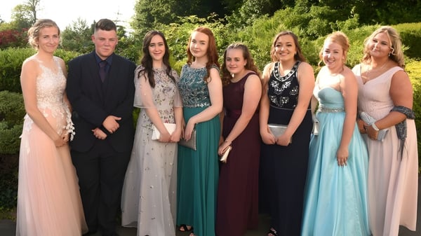 Un grupo de personas elegantemente vestidas posan al aire libre en el terreno de la St. Felix School.
