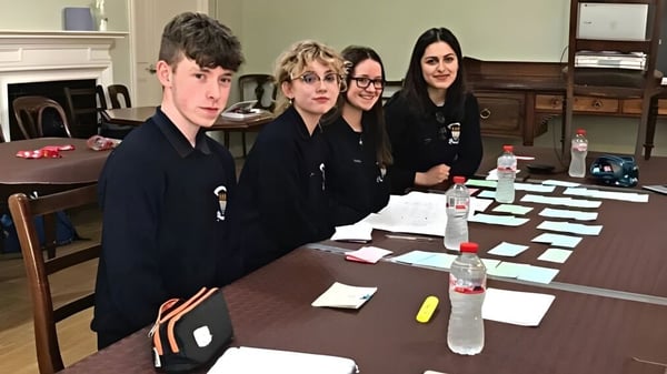 Estudiantes del St. Finian’s College Mullingar discuten juntos en una mesa en un aula.