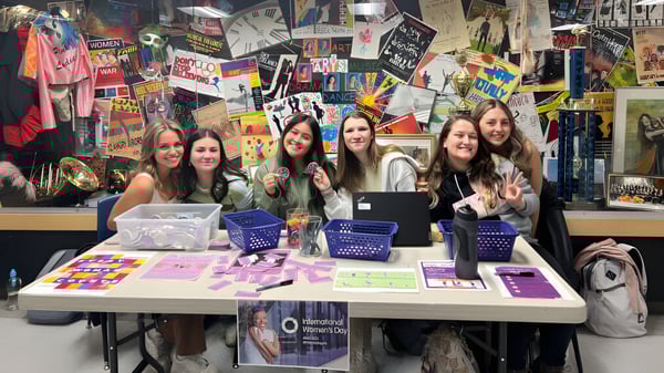 Estudiantes de la St. Francis High School se reúnen alrededor de una mesa con productos coloridos y carteles en el área de ventas.