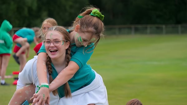 Dos alumnas se abrazan riendo en un prado en el campus de St. George's Ascot.