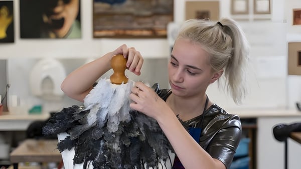 Una estudiante de la St. George's School Edimburgo examina una pieza de disfraz con plumas en el estudio de arte.