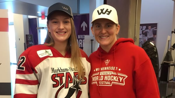 Dos estudiantes de la St. James' Regional High llevan camisetas deportivas y gorras en un pasillo.