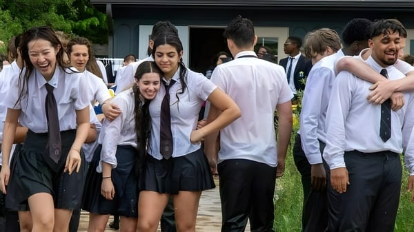 Un grupo de estudiantes está afuera frente a un edificio en el campus de la St. John’s-Kilmarnock School.