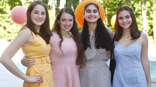 Cuatro estudiantes de la St. John's School están juntas en un área verde al aire libre.