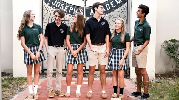 Un grupo de estudiantes está frente al edificio de la St. Joseph Academy con el letrero Joseph's Den.