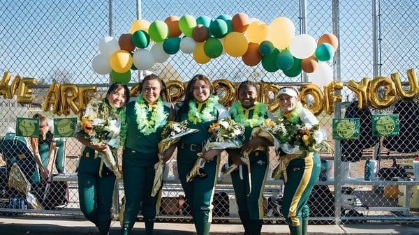 Un grupo de estudiantes de la St. Joseph Catholic High School está frente a un banner que dice 'We are the champions'.