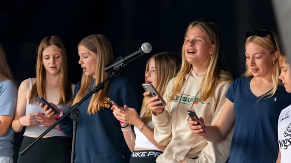 Un grupo de alumnas del St. Joseph's College realiza un programa en el escenario con micrófonos.