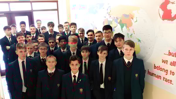 Un grupo de estudiantes de la St. Joseph's Secondary School está de pie frente a un mapa del mundo en la pared.