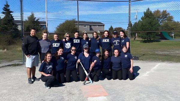 Un grupo de alumnas y alumnos de St. Kevin's High School están juntos en un campo deportivo frente a edificios y árboles.