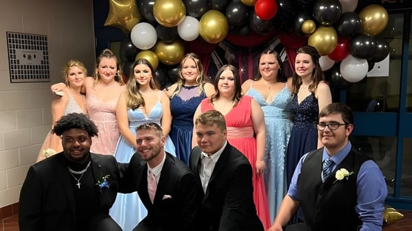 Un grupo de estudiantes de la St. Lawrence Secondary School posan frente a un colorido fondo de globos.
