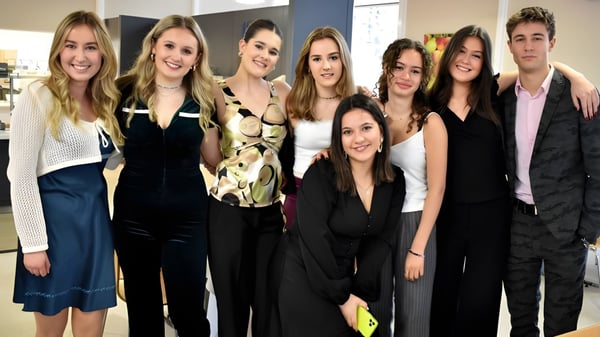 Un grupo de estudiantes se encuentra junto a un fondo neutral en el campus de la St. Leonards School.