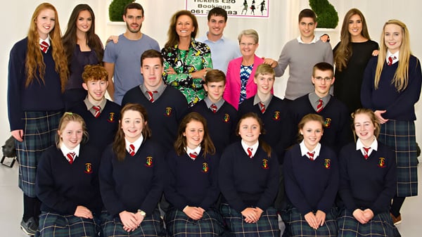 Un grupo de estudiantes de la St. Louis Community School posan juntos en el aula con carteles educativos de fondo.