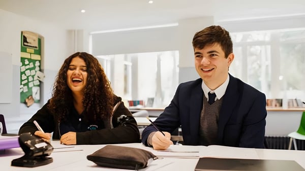 Dos jóvenes están sentados en un escritorio en una oficina en el campus de la St. Margaret’s School.