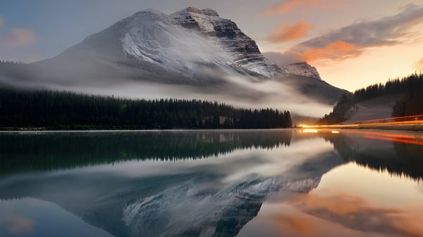 Una cima de montaña cubierta de nieve se refleja en un lago tranquilo en el terreno de la St. Mark High School.