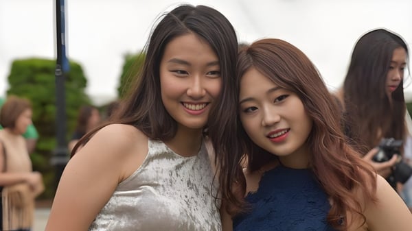 Dos alumnas con largas cabelleras oscuras sonríen juntas frente a áreas verdes en el campus de la St. Mark's School.