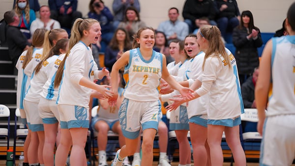 Un grupo de jugadoras de baloncesto de la St. Mary Catholic High School celebra juntas en la cancha de baloncesto.