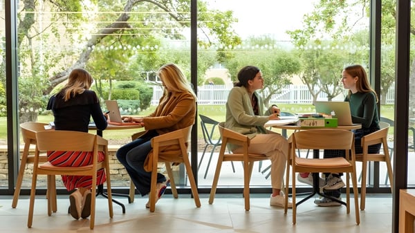 Un grupo de alumnas de St. Mary's Calne se sienta en una acogedora cafetería con gran vegetación a través de las ventanas.