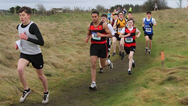 Alumnos de St. Mary’s College Ballysadare corren por un sendero boscoso cubierto de hierba en el terreno.