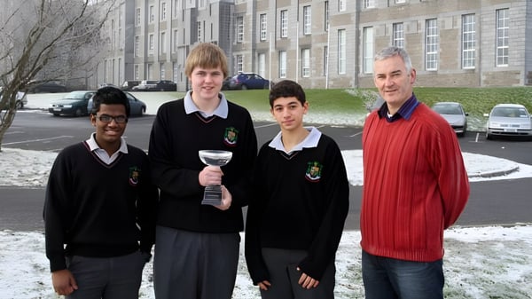 Cuatro estudiantes en uniformes escolares están de pie en la nieve frente a un edificio en el campus del St. Marys College Galway.
