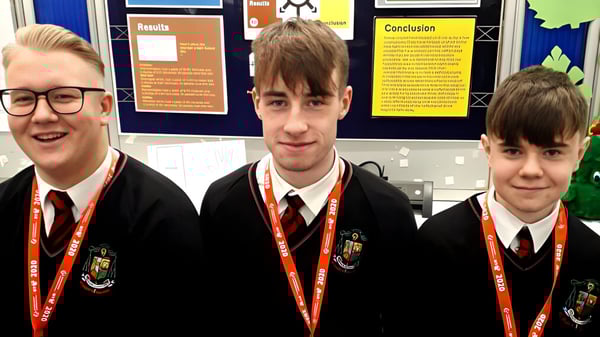 Tres estudiantes en uniforme escolar están frente a un tablero de información en el campus del St. Marys College Galway.