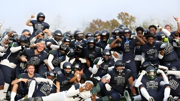 Un grupo de jugadores de fútbol en uniforme está en el campo de St. Mary's Ryken High School.