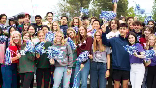 Estudiantes de St. Mary's School se reúnen afuera con pompones azules y blancos como equipo de animadoras.