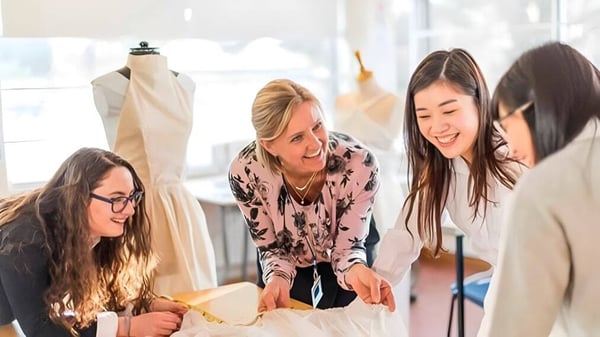 Estudiantes de la St. Mary's School trabajan juntas en un estudio de diseño de moda con máquinas de coser.