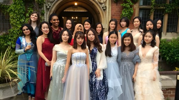 Un grupo de jóvenes mujeres vestidas de forma formal se encuentra frente al histórico edificio de ladrillo de la St. Mary's School.