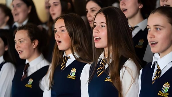 Un grupo de alumnas y alumnos de St. Mary’s Secondary está en coro y lleva uniformes escolares.