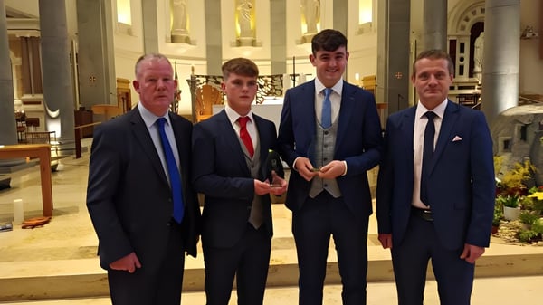 Cuatro hombres en trajes formales están juntos en el interior de St. Mel’s College.