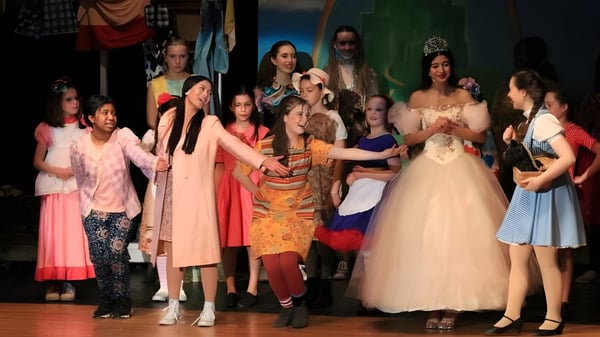 Un grupo de estudiantes en vestidos coloridos realiza una actuación en el escenario de la St. Mother Teresa High School.