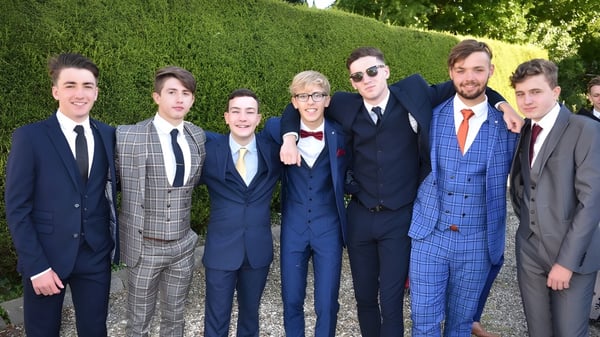 Un grupo de personas está en el jardín del St. Patrick's College durante un evento formal.