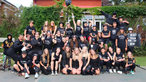 Un gran grupo de estudiantes de la St. Patrick’s High School en Québec City posa frente a un edificio de ladrillo con áreas verdes.