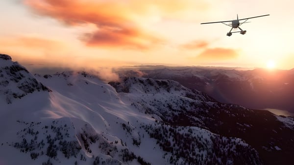 Un pequeño avión vuela sobre un paisaje montañoso cubierto de nieve al atardecer cerca de la St. Peter High School.