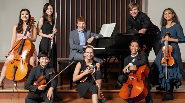 Un grupo de músicos de la St. Peter’s High School toca varios instrumentos en un escenario con fondo de madera.