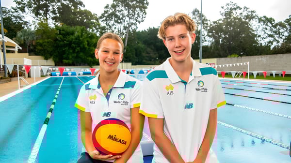 Dos jóvenes atletas están junto a una piscina al aire libre con un balón de voleibol en la mano en el campus de St. Peters Lutheran College.