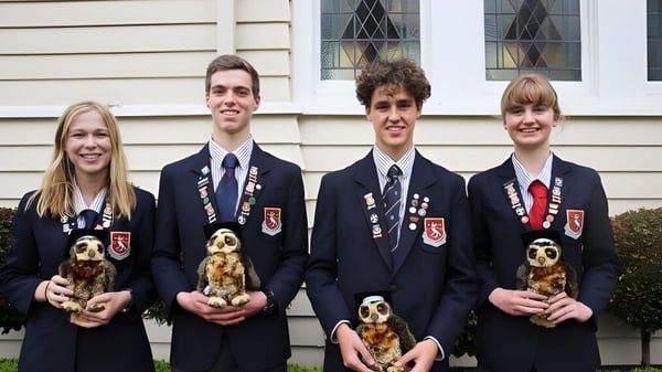 Cuatro alumnas y alumnos de la St. Peter's School Cambridge están frente a un edificio de madera y cada uno sostiene un perro pequeño.